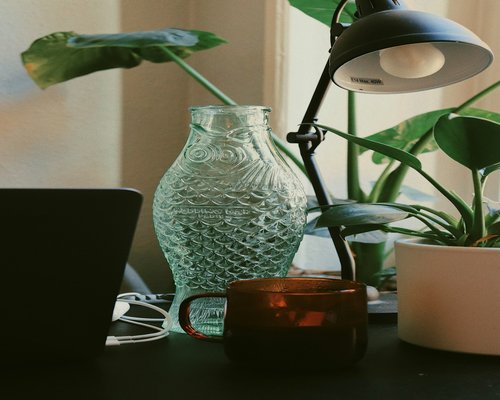A clean desk setup with a warm lamp and a glass of water, showing a healthy work environment